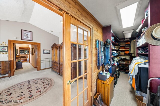 spacious closet featuring light carpet and lofted ceiling with skylight