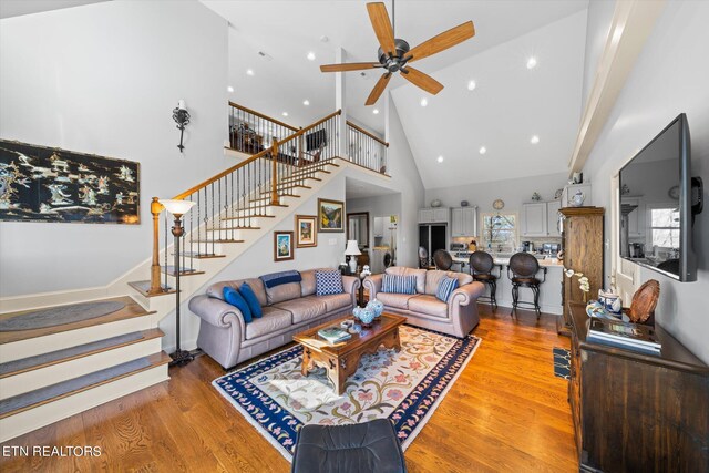 living room with high vaulted ceiling, ceiling fan, and wood-type flooring