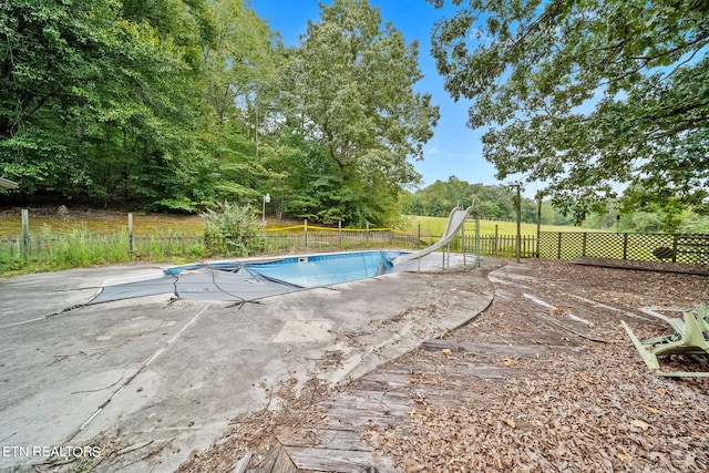 view of swimming pool featuring a water slide and a patio area