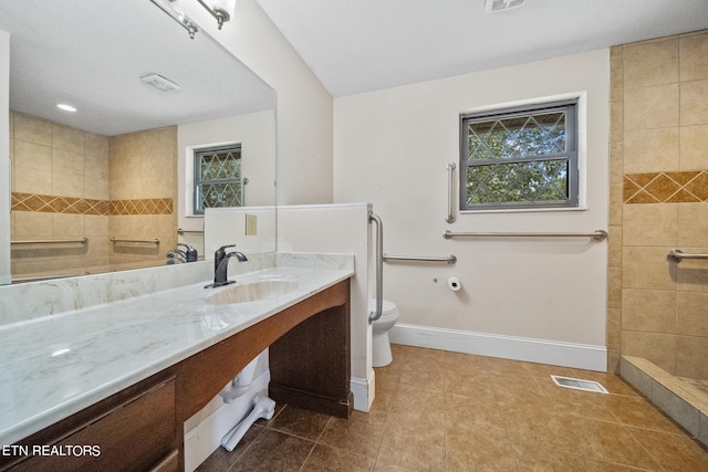 bathroom featuring tiled shower, vanity, toilet, and tile patterned flooring