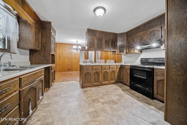 kitchen featuring an inviting chandelier, electric range, sink, kitchen peninsula, and a textured ceiling