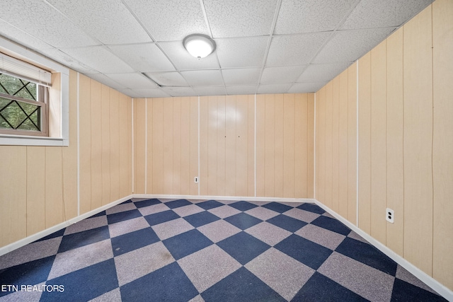 empty room featuring a paneled ceiling and wooden walls