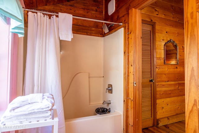 bathroom with wooden walls, hardwood / wood-style floors, and shower / tub combo