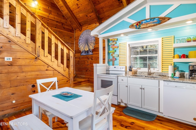 kitchen featuring white cabinets, white appliances, wood walls, vaulted ceiling with beams, and sink