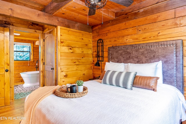 bedroom with wood ceiling, beamed ceiling, ensuite bathroom, hardwood / wood-style flooring, and wooden walls