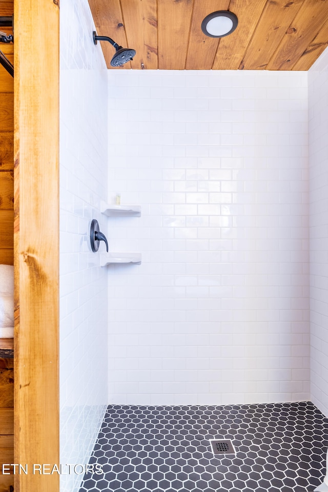 bathroom with wood ceiling and a tile shower