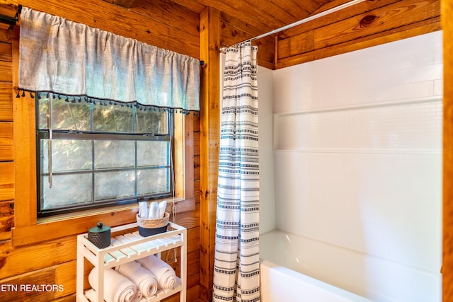 bathroom featuring wood walls and shower / tub combo