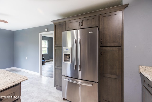 kitchen with ceiling fan, light stone counters, dark brown cabinets, and stainless steel refrigerator with ice dispenser