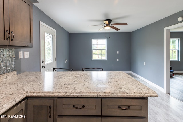 kitchen featuring ceiling fan, light stone counters, plenty of natural light, and light hardwood / wood-style flooring