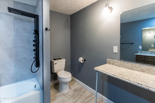 full bathroom with tiled shower / bath, toilet, wood-type flooring, vanity, and a textured ceiling