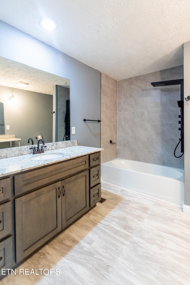 bathroom featuring tiled shower / bath, vanity, and a textured ceiling