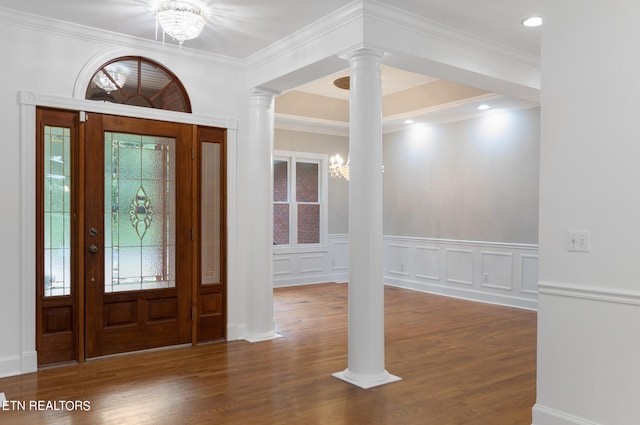 entrance foyer featuring an inviting chandelier, hardwood / wood-style flooring, ornate columns, and crown molding