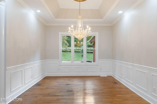 unfurnished room featuring ornamental molding, a notable chandelier, wood-type flooring, and a tray ceiling