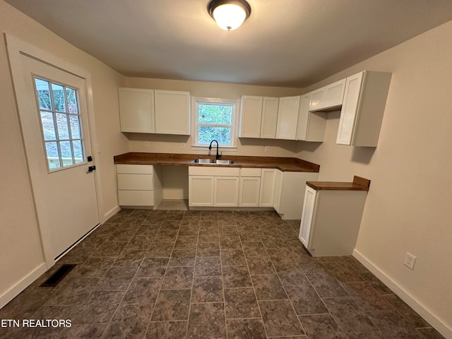 kitchen featuring white cabinetry, wood counters, and sink