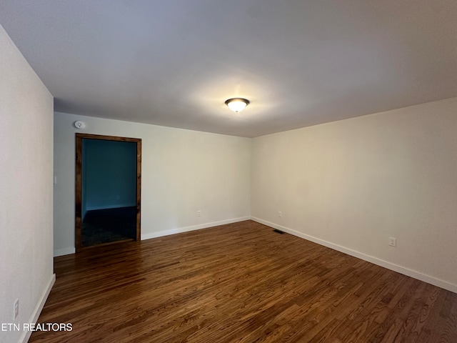 unfurnished room featuring dark wood-type flooring