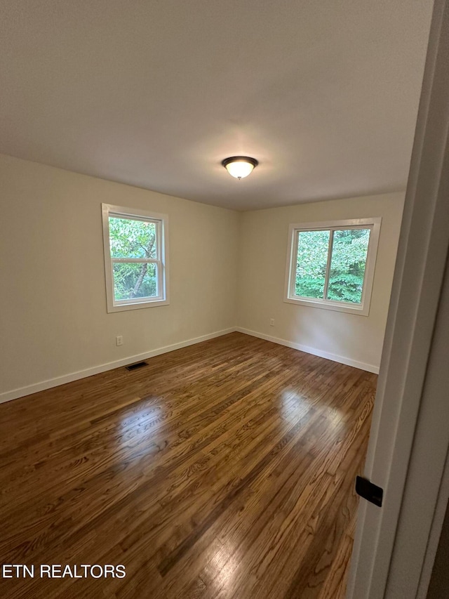 unfurnished room with dark wood-type flooring