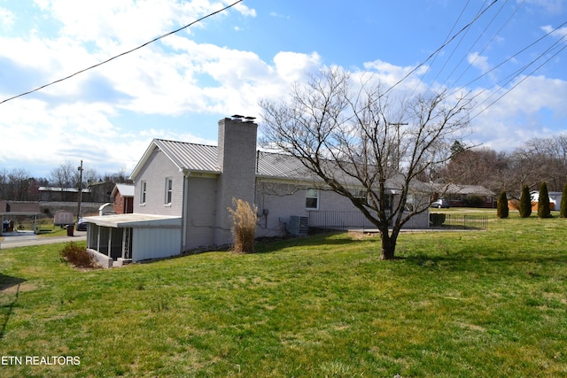 view of property exterior with a yard, central air condition unit, metal roof, and a standing seam roof