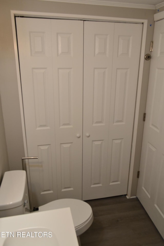 half bath featuring toilet, wood finished floors, and crown molding