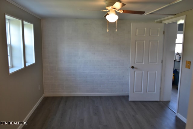 unfurnished room featuring ceiling fan, baseboards, brick wall, and dark wood-style flooring