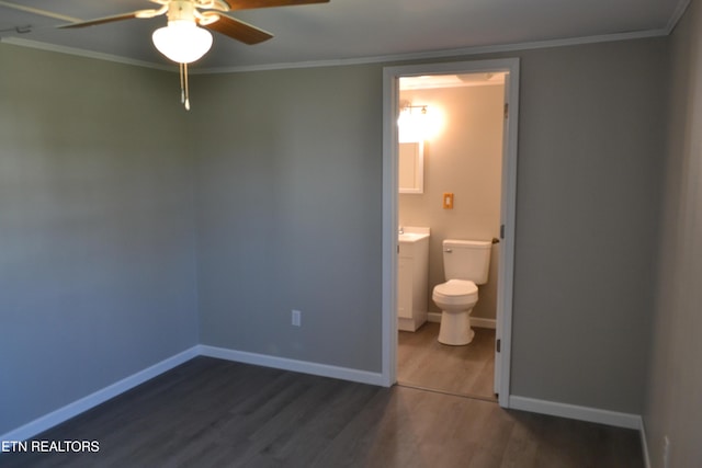 unfurnished bedroom with crown molding, baseboards, dark wood-style flooring, and ensuite bathroom