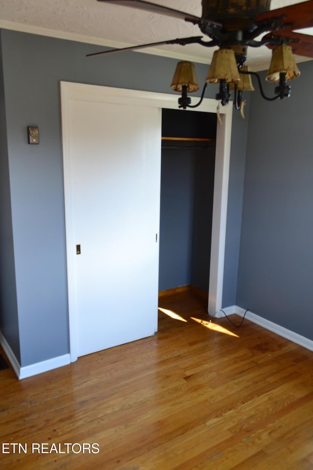 unfurnished bedroom with a closet, baseboards, and wood finished floors