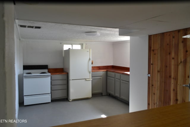 kitchen with gray cabinetry, finished concrete flooring, crown molding, butcher block countertops, and white appliances