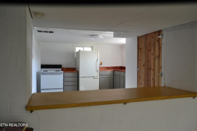 kitchen featuring visible vents, white appliances, a peninsula, and butcher block counters