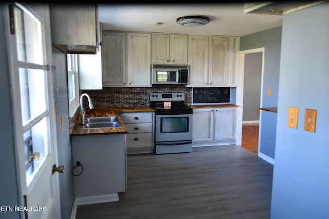 kitchen featuring backsplash, dark wood-type flooring, butcher block counters, appliances with stainless steel finishes, and a sink