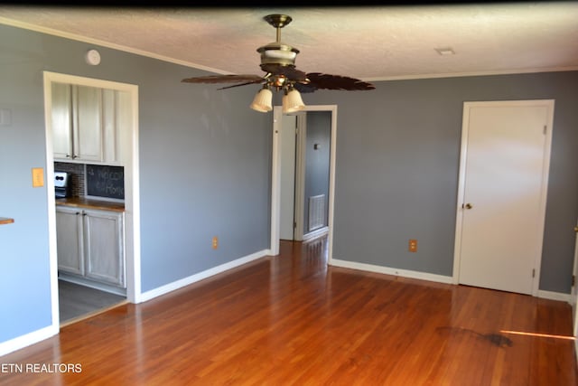 unfurnished room with wood finished floors, baseboards, and ornamental molding