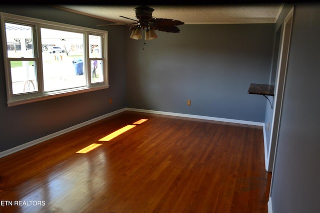 empty room with baseboards, dark wood-style flooring, and ceiling fan