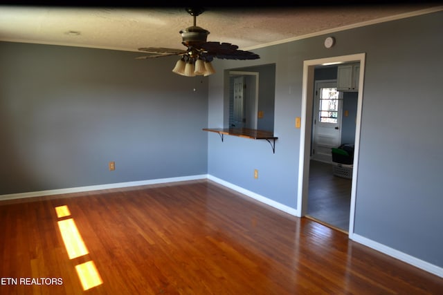 empty room featuring crown molding, wood finished floors, baseboards, and a textured ceiling