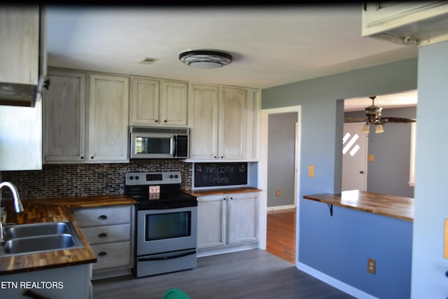 kitchen with a sink, decorative backsplash, stainless steel appliances, and butcher block counters