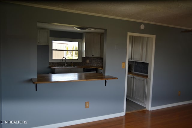 kitchen with wood counters, a breakfast bar, dark wood-style floors, and a sink