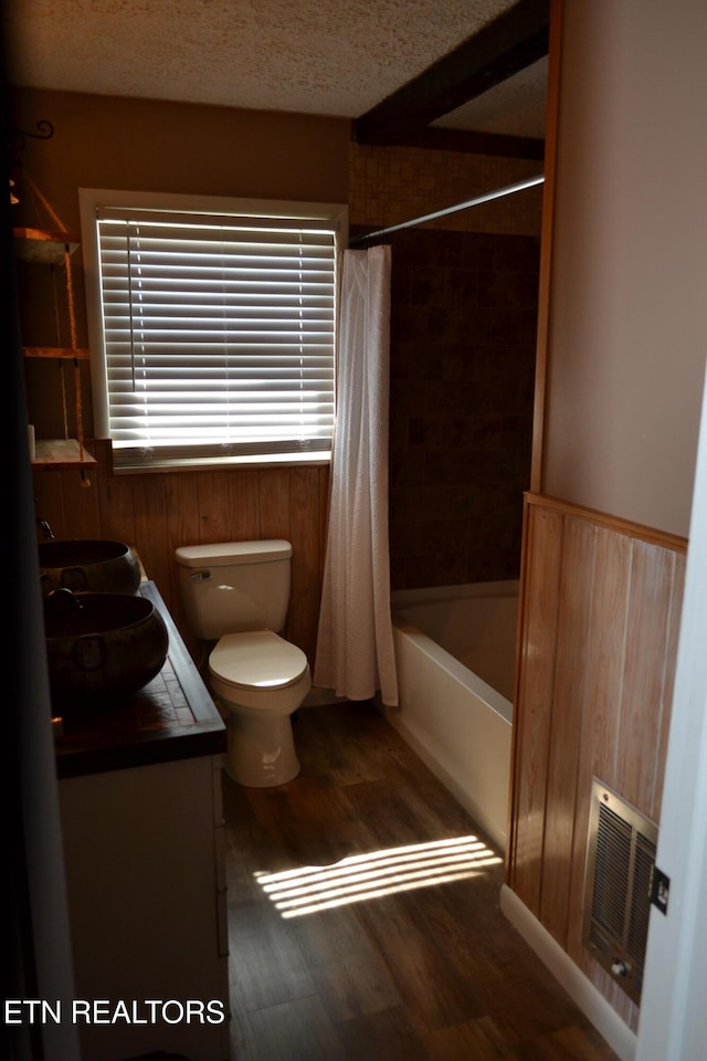 bathroom with visible vents, toilet, shower / tub combo with curtain, a textured ceiling, and wood finished floors