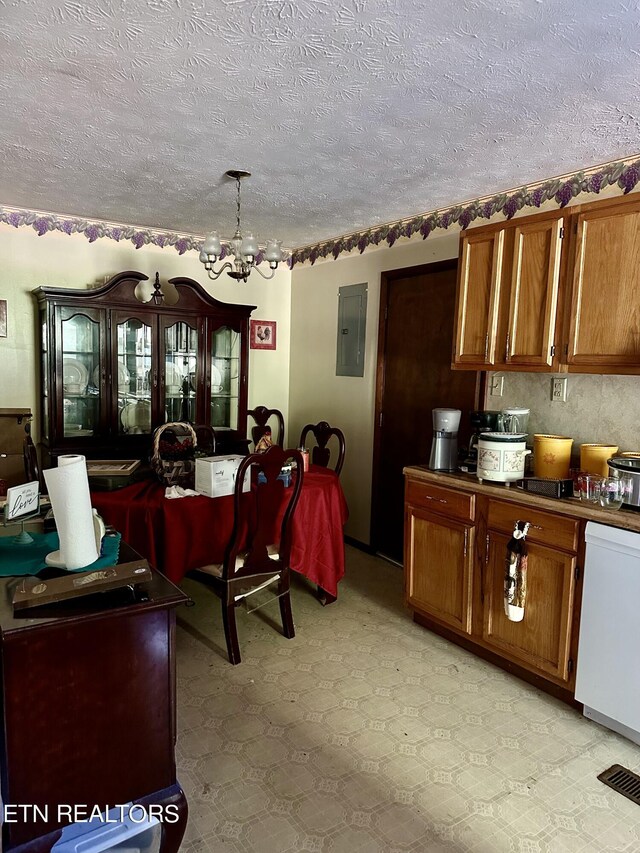 kitchen with a textured ceiling, electric panel, a chandelier, and brown cabinetry