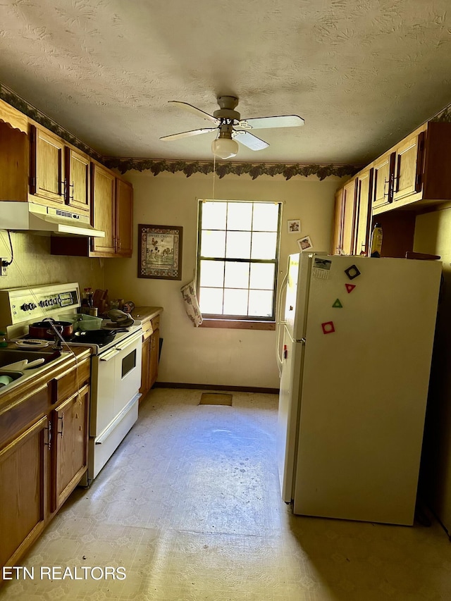kitchen with a ceiling fan, a textured ceiling, under cabinet range hood, and white appliances