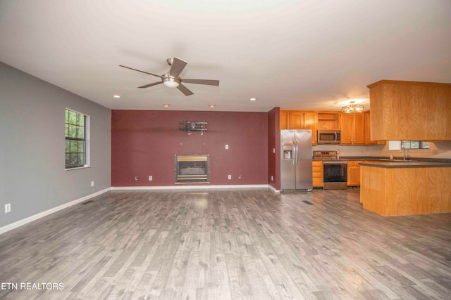 kitchen with sink, dark wood-type flooring, kitchen peninsula, ceiling fan, and stainless steel appliances