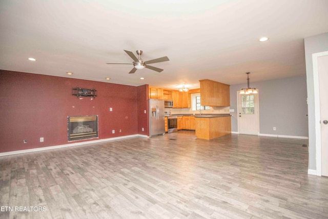 unfurnished living room featuring ceiling fan, sink, and light wood-type flooring