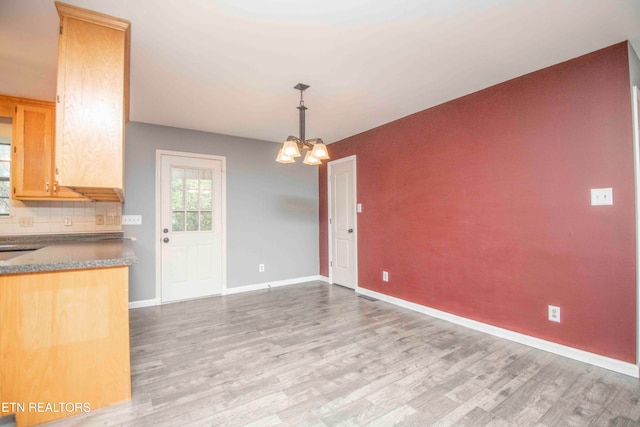 kitchen with light hardwood / wood-style flooring, a chandelier, tasteful backsplash, and pendant lighting