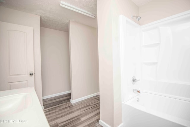 bathroom featuring a textured ceiling, hardwood / wood-style flooring, and tub / shower combination