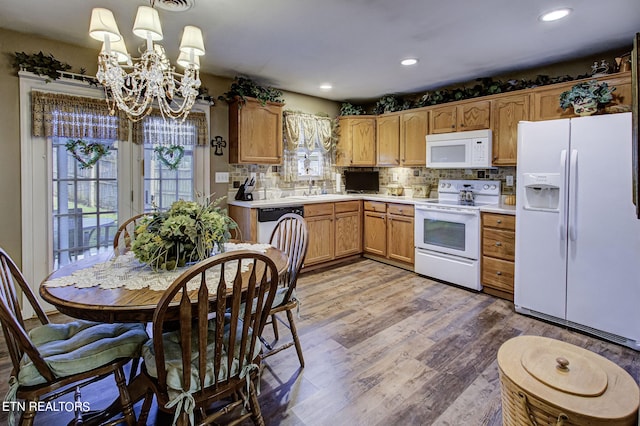 kitchen featuring decorative light fixtures, tasteful backsplash, hardwood / wood-style flooring, white appliances, and an inviting chandelier