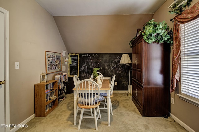 dining space with baseboards, light carpet, and vaulted ceiling