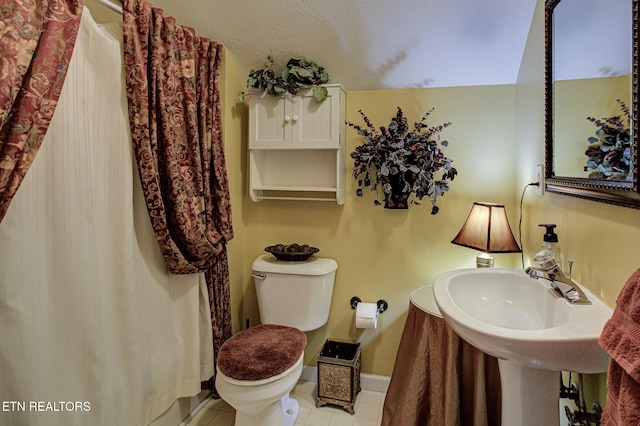 bathroom with a sink, baseboards, toilet, and tile patterned flooring