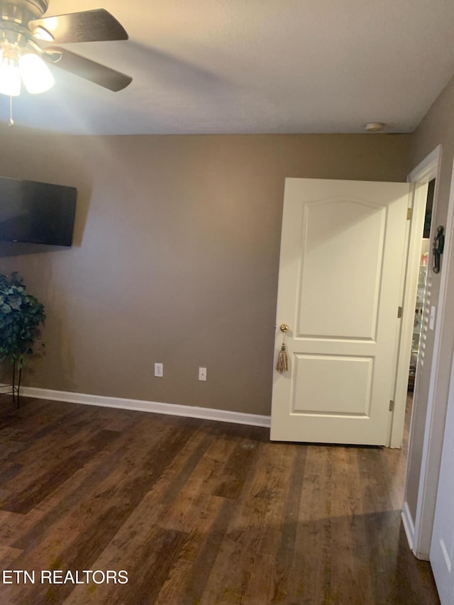 unfurnished room featuring a ceiling fan, dark wood-type flooring, and baseboards