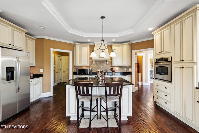 kitchen with cream cabinets, a kitchen island, hanging light fixtures, stainless steel appliances, and dark wood-type flooring