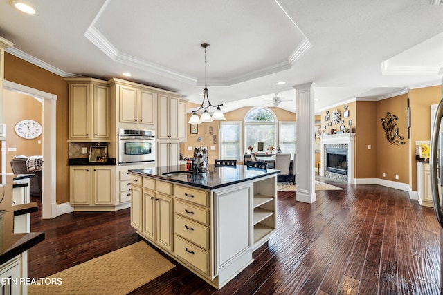 kitchen with oven, wood-type flooring, cream cabinetry, a kitchen island, and a raised ceiling