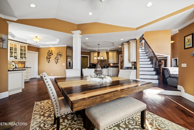 dining area featuring decorative columns, a tray ceiling, vaulted ceiling, ornamental molding, and dark hardwood / wood-style floors