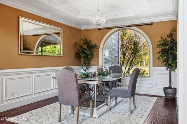 dining area featuring a chandelier, crown molding, wood-type flooring, and a tray ceiling