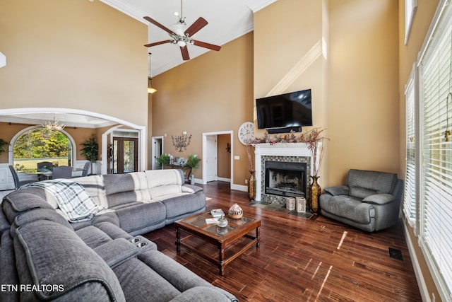 living room with crown molding, a fireplace, a towering ceiling, and dark hardwood / wood-style flooring