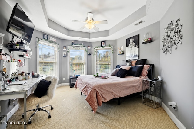 bedroom featuring carpet flooring, a tray ceiling, and ceiling fan